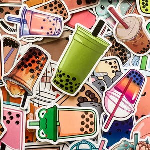May include: A collection of colorful stickers featuring various bubble tea designs. The stickers feature different colors, patterns, and designs, including green, pink, orange, and blue. Some stickers feature cartoon characters, while others feature simple designs of bubble tea cups.