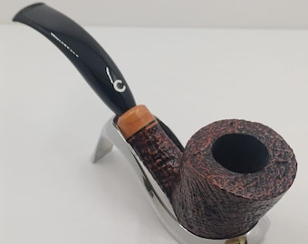 May include: A tobacco pipe with a dark brown bowl and a black stem, on a silver stand. The bowl has a textured surface, and the stem is curved. The pipe is designed for smoking.