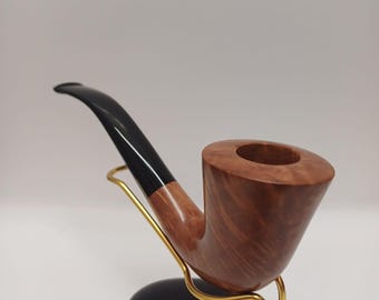 Pode incluir: Um cachimbo de madeira marrom com bocal preto, apoiado em um suporte preto e dourado.