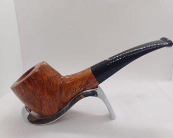 Pode incluir: Um cachimbo de tabaco castanho e preto com uma haste curva, apoiado num suporte prateado. O cachimbo tem uma tigela de madeira e um bocal preto. O texto "L. Vivante Made in Italy" é visível.
