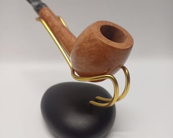 May include: A wooden pipe with a brown finish and a black mouthpiece is displayed on a black stand with a gold metal holder.