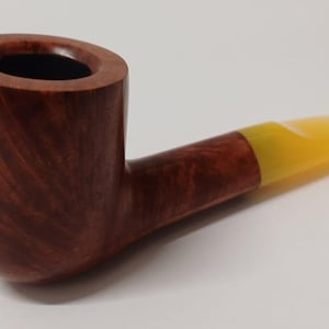May include: A brown wooden pipe with a yellow acrylic stem. The pipe has a bowl and a long, curved stem.