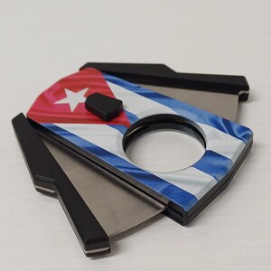Può includere: Tagliasigari con il design della bandiera cubana. Il tagliasigari presenta un motivo a bandiera rosso, bianco e blu con una stella bianca. Le lame sono argentate e l'impugnatura è nera.