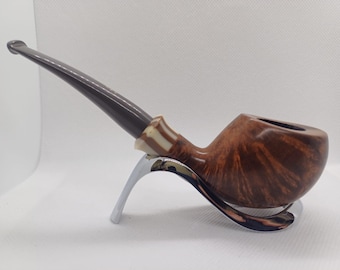 May include: A brown tobacco pipe with a dark stem and a light-colored band. The pipe rests on a silver stand, showcasing its curved design and wood grain. The pipe is a classic smoking accessory.