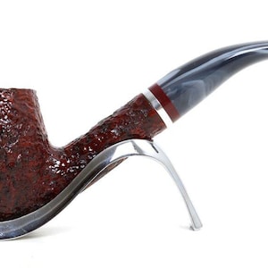 May include: A brown tobacco pipe with a textured bowl and a curved stem. The stem is gray and white with a red and silver band. The pipe rests on a silver stand.