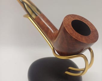 May include: A brown wooden pipe with a gold-coloured band and a black bowl. The pipe is on a black stand with a gold-coloured metal hook.