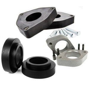 May include: A set of four black and silver car suspension lift spacers. The spacers are made of metal and rubber and are designed to raise the height of a vehicle.
