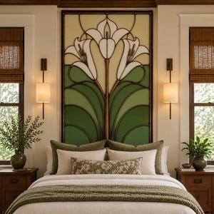 May include: A bedroom featuring a large rectangular stained glass panel with a white lily floral design and green foliage. The bed is dressed in white linens, olive green pillows, a textured olive green throw, and a floral patterned lumbar pillow.
