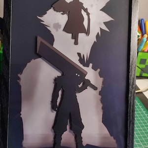 Peut inclure: Œuvre encadrée avec des silhouettes superposées de personnages de jeux vidéo. Une silhouette sombre avec une grande épée au premier plan, une autre figure au-dessus. Le fond est un dégradé bleu foncé et blanc, dans un cadre noir.