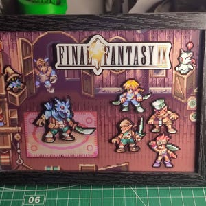 Puede incluir: Una obra de arte enmarcada con personajes de píxeles de Final Fantasy IX. La escena incluye varios personajes y el logotipo del juego. El marco es negro y el fondo es una escena interior detallada.