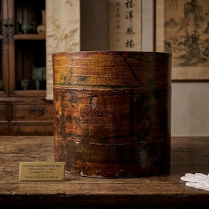 Peut inclure: Une boîte à chapeau cylindrique en laque brune de la dynastie Qing, ornée d'une scène peinte à la main représentant une personne jouant d'un instrument à cordes parmi des arbres. Une plaque indique : CHINESE LACQUERED HAT BOX QING DYNASTY, c. 18th C.