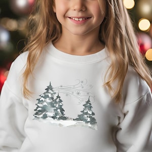May include: White sweatshirt for kids features a watercolor-style winter scene with two evergreen trees and snowflakes. The design is subtle and charming, perfect for the holiday season.  The sweatshirt is soft and comfortable, ideal for everyday wear or special occasions.  A great gift for children who love winter and nature.