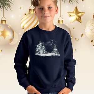 May include: Navy blue crew neck sweatshirt with a winter landscape design. The image shows snow-covered trees and swirling snowflakes in shades of grey and white. A festive garment.