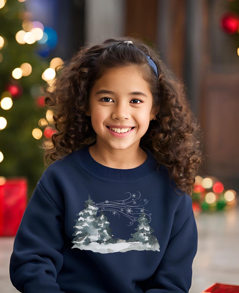 May include: Navy blue children's sweatshirt featuring a watercolor-style winter scene. The design showcases two stylized evergreen trees in a snowy landscape, with snowflakes and windswept lines adding to the wintery theme. The sweatshirt is a comfortable crewneck style, perfect for the holiday season.