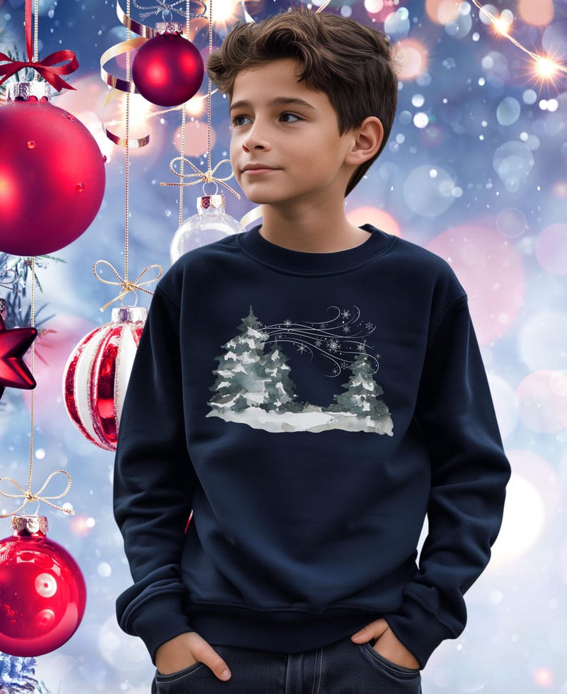 May include: A navy blue sweatshirt with a winter landscape design. The graphic shows snow-covered trees and snowflakes in grey and white. The sweatshirt has a crew neck.