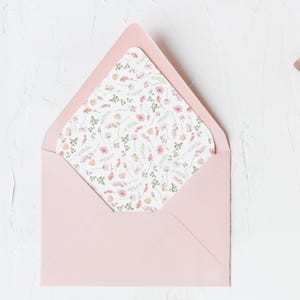 May include: A pink envelope with a floral pattern lining the inside. The envelope is lying flat on a white surface.