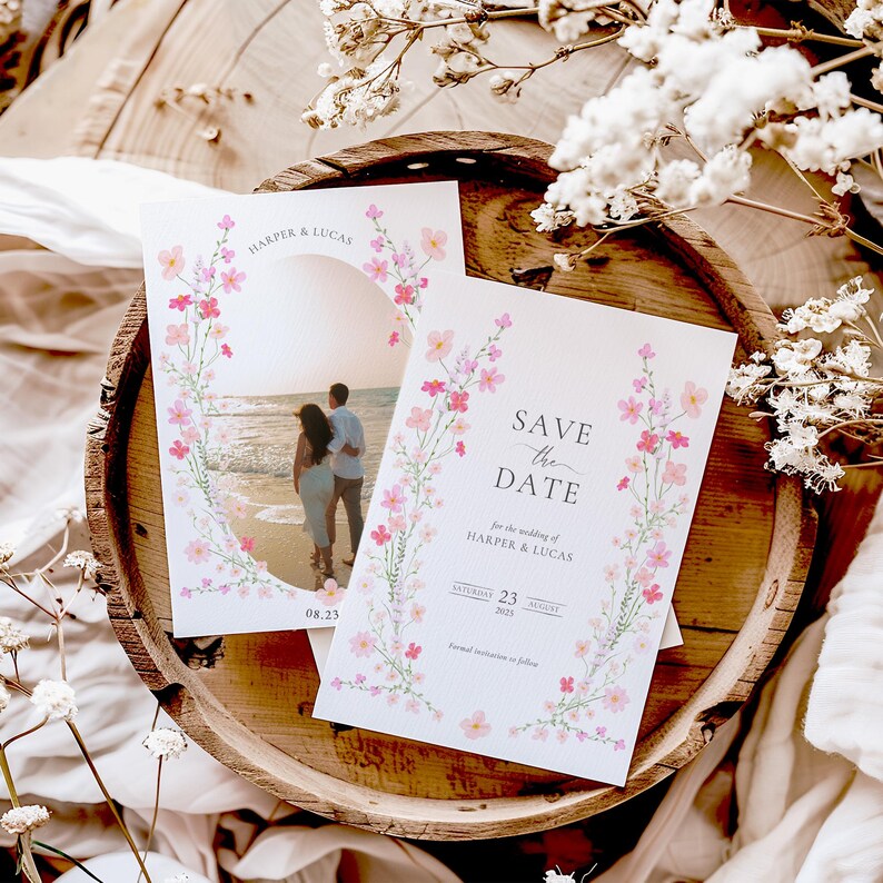 Op de afbeelding: Save the date-kaart met een bloemenontwerp en een foto van een stel op het strand. De kaart staat "Save the Date" voor de bruiloft van Harper & Lucas, zaterdag 23 augustus 2023.