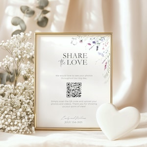 Pode incluir: Um cartão branco com moldura dourada e um design floral. O cartão diz "Share the Love" e tem um código QR. O texto abaixo do código QR diz "Basta escanear o código QR e carregar suas fotos e vídeos. Obrigado por nos mostrar seu ponto de vista!" O cartão é assinado "Emily e William" e a data "JULY 15th 2025".
