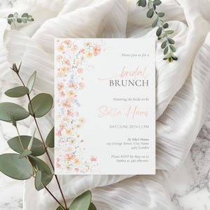 Puede incluir: Una invitación a un brunch de boda con un borde floral rosa y azul. El texto dice "Por favor, únase a nosotros para un brunch de boda en honor a la futura novia Stella Harris SÁB | 28 DE JUNIO | 1 PM En la casa de Isla 123 Cottage Street, City Name 4567 Londres Por favor, confirme su asistencia antes de mayo a Sophia al 456-789-000"