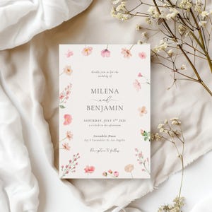 May include: A wedding invitation with a floral design featuring pink flowers and greenery. The invitation reads "Kindly join us for the wedding of Milena and Benjamin, Saturday, July 5th, 2025, 2 o'clock in the afternoon, Carondelet House, 625 S Carondelet St, Los Angeles, Reception to follow."