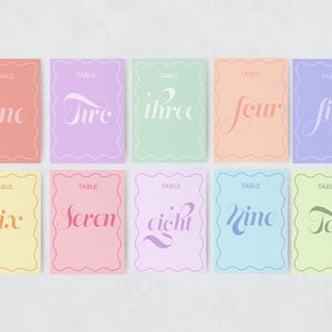 May include: Ten table number cards with scalloped edges. The cards are in pastel colors and feature the numbers one through ten written in a cursive font. The cards are perfect for a wedding, party, or other event.