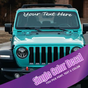 May include: A turquoise Jeep Wrangler with a white windshield decal that says "Your Text Here". The decal is a single color decal, and you can choose the font, text, and color.