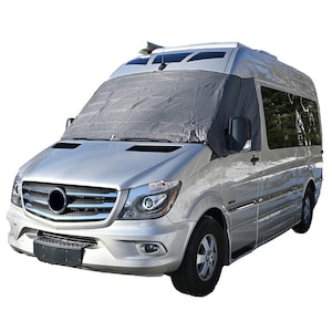 May include: A silver van with a grey windscreen cover. The van has a black grille and headlights.
