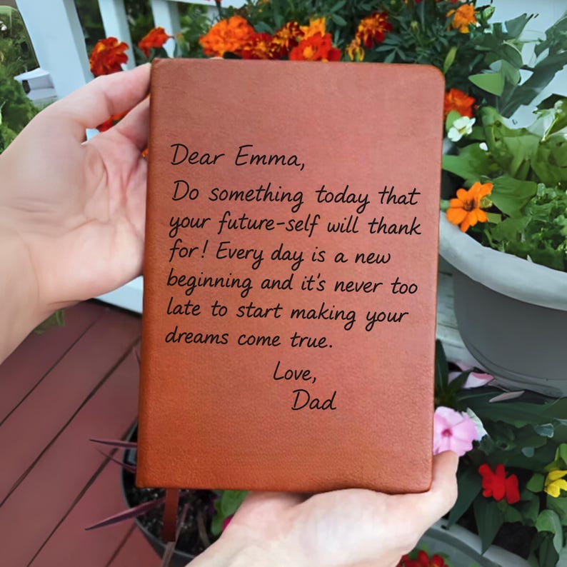 May include: A brown leather-bound journal with the inscription "Dear Emma, Do something today that your future-self will thank for! Every day is a new beginning and it's never too late to start making your dreams come true. Love, Dad."