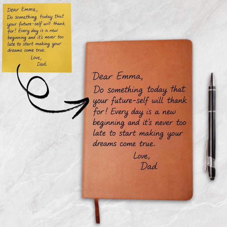 May include: A brown leather-bound notebook with a ribbon bookmark and a black pen. The notebook has the text "Dear Emma, Do something today that your future-self will thank for! Every day is a new beginning and it's never too late to start making your dreams come true. Love, Dad."