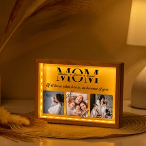 Puede incluir: Un marco de fotos de madera con una luz cálida que ilumina tres fotos y el texto "MOM" con los nombres "Mathew, Jesicca, Daniel" y la cita "Si sé lo que es el amor, es por ti."