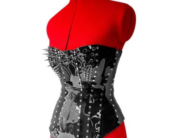 May include: A black, glossy, strapless corset featuring a structured bodice adorned with numerous silver-toned metal spikes on the chest area and vertical rows of silver-toned studs along the seams and edges, creating a sharp, metallic aesthetic.