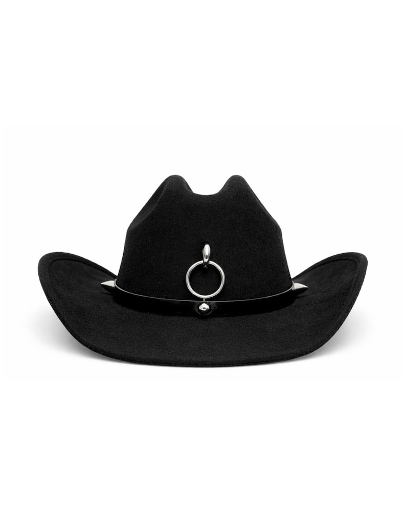 Puede incluir: Un sombrero de vaquero negro con un anillo y tachuelas plateadas. El sombrero tiene un ala curvada y un anillo decorativo plateado en la parte delantera. El sombrero es de fieltro.