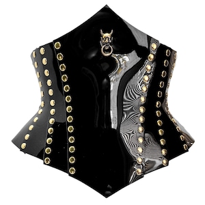 May include: Black corset with gold-colored studs and a devil skull charm. The corset has a glossy finish and a unique shape, with a pointed top and a structured design. The studs are evenly spaced along the edges.