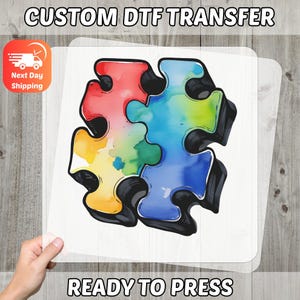 May include: A ready-to-press DTF transfer with a colourful jigsaw puzzle design. The puzzle pieces are in red, yellow, green, and blue with black outlines. The text "CUSTOM DTF TRANSFER" and "READY TO PRESS" are visible.