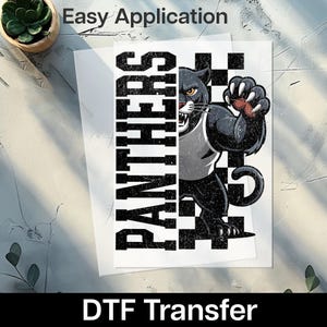 May include: A DTF transfer featuring a black panther graphic with the word "PANTHERS" in bold, distressed white letters. The panther is in a dynamic pose, with a checkered background. The words "Easy Application" and "DTF Transfer" are also visible.