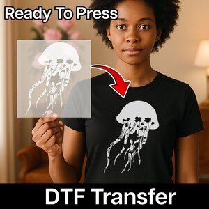 May include: A black t-shirt featuring a white graphic of a jellyfish filled with floral patterns. A transparent sheet displays the same jellyfish design, labelled Ready To Press DTF Transfer, indicating a heat-applied transfer for fabric application.