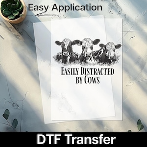 May include: A DTF transfer featuring three black and white cow illustrations. The text "EASILY DISTRACTED BY COWS" is below the cows. The words "Easy Application" are at the top of the image.