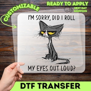May include: A DTF transfer with a cartoon cat illustration and the text "I'M SORRY, DID I ROLL MY EYES OUT LOUD?". The cat is depicted in black and white with yellow eyes. The transfer is ready to apply and customizable.