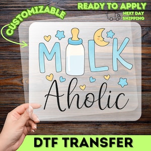 May include: A DTF transfer with the words "MILK Aholic" in a playful font, featuring a baby bottle, stars, and hearts. The design is in blue, yellow, and black, with the words "Ready to Apply" and "Next Day Shipping".