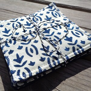 May include: Set of six blue and white fabric coasters with a geometric pattern. The coasters are tied together with twine.