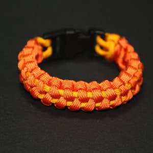 May include: A bright orange and yellow paracord bracelet with a black plastic clasp.