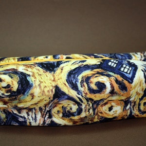 May include: A yellow, blue and white zippered pouch with a swirling pattern reminiscent of Van Gogh's Starry Night. The pouch has a white zipper pull and a white strap.