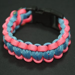May include: A blue and pink paracord bracelet with a black plastic clasp.