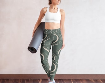 Puede incluir: Un sujetador deportivo blanco de espalda nadadora y unos leggings de talle alto con base verde salvia oscuro y un patrón de líneas onduladas de color crema. Los leggings se combinan con una esterilla de yoga gris oscuro enrollada y zapatillas deportivas grises.