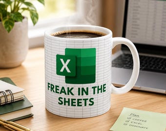 May include: A white ceramic mug featuring a green Microsoft Excel logo and the text "FREAK IN THE SHEETS" printed in green. The mug has a grid pattern background resembling a spreadsheet and is filled with a dark brown liquid.