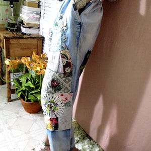 May include: Light blue denim pants with a patchwork design featuring lace, floral fabric, and other embellishments. The pants have a wide leg and a relaxed fit.