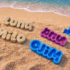 Peut inclure: Des lettres de sable épellent "Luna" et "Milo" sur une plage. Des moules à noms violets et bleus épellent "Amy" et "Olin". Une pelle bleue est également dans le sable près de l'eau.