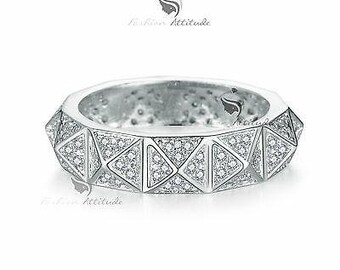 May include: A silver ring with a geometric design featuring a row of triangular shapes set with clear cubic zirconia stones.