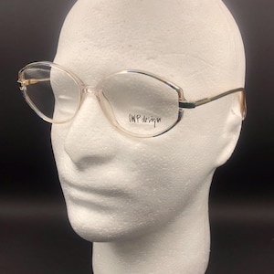 Op de afbeelding: Transparante bril met een montuur van kunststof en gouden accenten, met de tekst "OWP design" op de rechterlens.