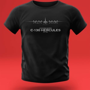 Könnte beinhalten: Schwarzes T-Shirt mit einer weißen Grafik eines Lockheed Martin C-130 Hercules Flugzeugs. Der Text "Lockheed Martin C-130 Hercules EST 1954" ist unter dem Flugzeug gedruckt.